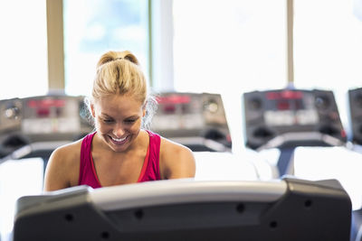 Happy woman operating treadmill at gym