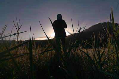Silhouette man standing on field against sky during sunset