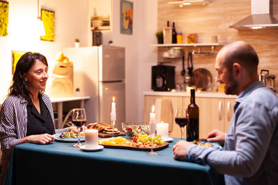 Side view of young woman having food at home