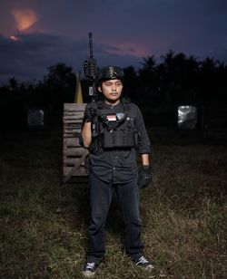 Portrait of man standing on field with gun