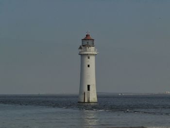 Lighthouse by sea against sky