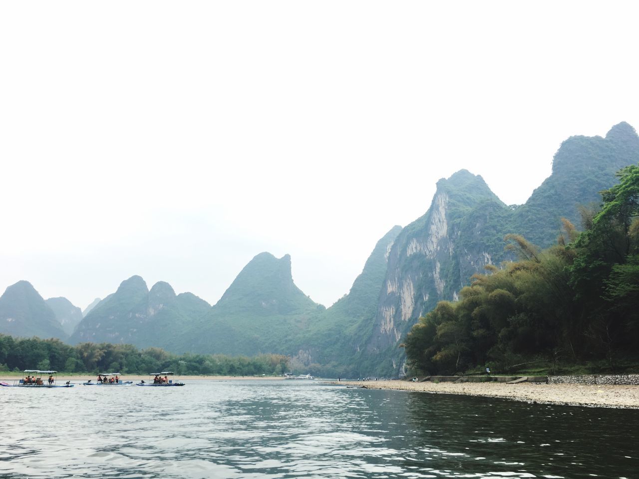 water, mountain, sky, beauty in nature, scenics - nature, nautical vessel, waterfront, mountain range, tranquility, tree, nature, transportation, tranquil scene, day, clear sky, river, plant, non-urban scene, outdoors, no people, formation