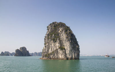 Rock formation in sea against clear sky