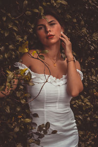 Young woman looking away while standing by leaves