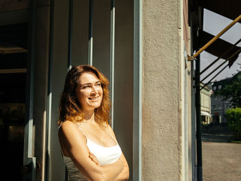 Portrait of young woman standing against wall