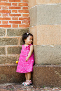 Girl standing against brick wall