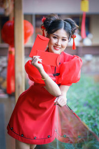 Woman holding red while standing against blurred background