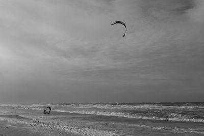 People kiteboarding on shore at beach against sky