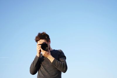 Man photographing against clear blue sky