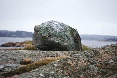 Close-up of rock by sea against sky