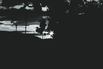 Silhouette people walking in park against sky at night