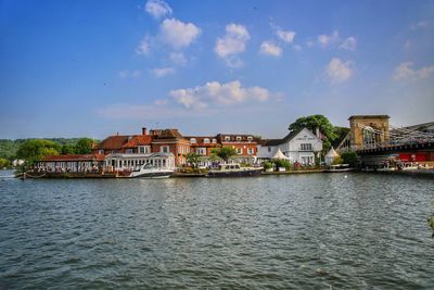 Buildings at waterfront against cloudy sky