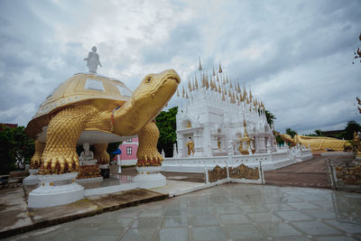 Statue outside temple against building and sky