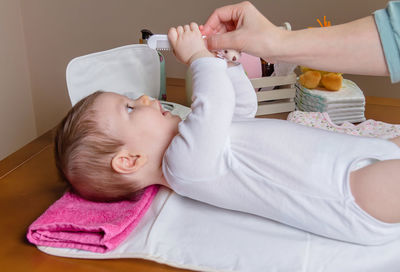 Woman combing baby girl at home