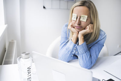Businesswoman sleeping while sitting by desk at home