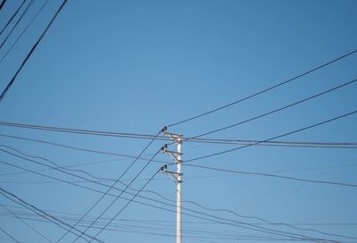 Low angle view of power lines against clear blue sky