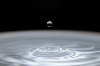 Close-up of water drop on table against black background