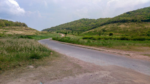 Road leading towards mountains against sky