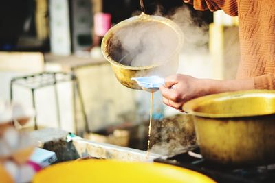 Midsection of man pouring tea in container