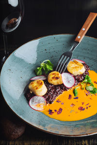 From above of appetizing haute cuisine delicacy served in ceramic plate with glass of red wine