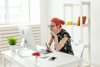 Woman looking away while sitting on table at home