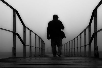 Full length rear view of woman standing by railing