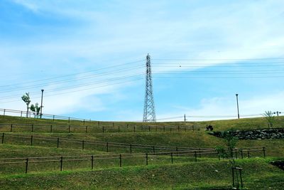 Electricity pylon on field against sky