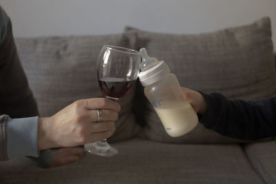 Cropped hand of father and son toasting wineglass and milk bottle