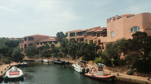 Boats moored on river by buildings in city against sky