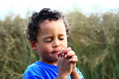 Cute boy praying against plants