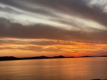 Scenic view of sea against dramatic sky during sunset