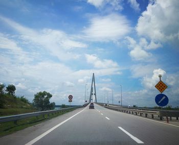 Road sign by bridge against sky