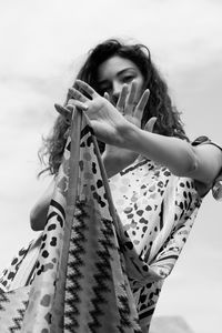 Young woman looking at camera against sky