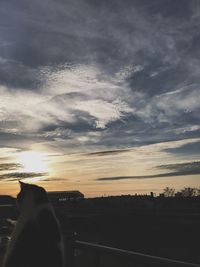 Low section of silhouette person against cloudy sky