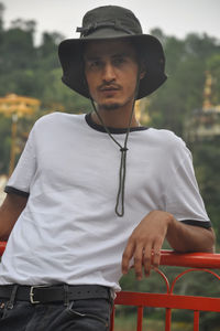 A indian young guy posing outdoor with wearing boonie hat and white tshirt and looking at camera 