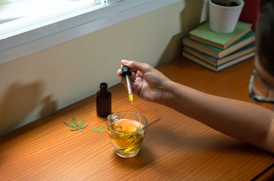 Midsection of woman holding drink on table