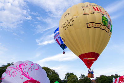 Low angle view of hot air balloons flying against sky