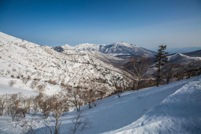 Scenic view of snow covered mountains against blue sky