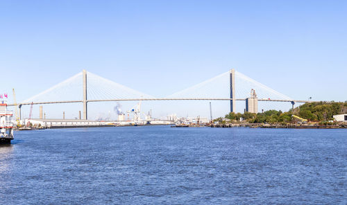 Suspension bridge over sea against clear blue sky