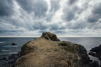 Rock formation on beach against sky