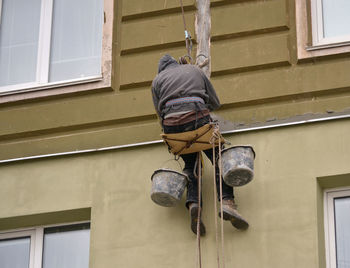 Low angle view of man working against building