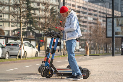 Rear view of man riding push scooter on street