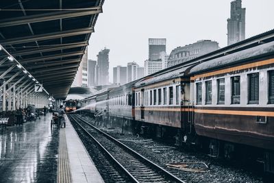 Train at railroad station in city against sky