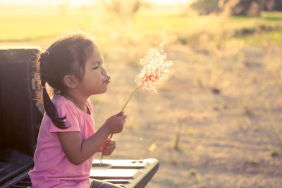 Girl blowing plants while sitting on bench