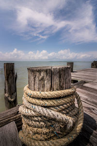 Stack of wooden post in sea against sky