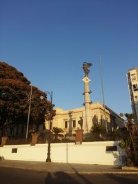 Statue in city against clear blue sky