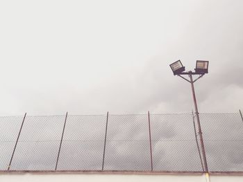 Low angle view of halogen lights by fence