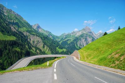 Country road amidst mountains against sky