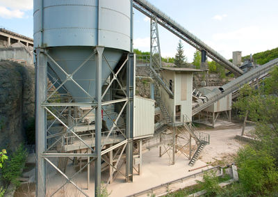 Metallic structure by abandoned building against sky