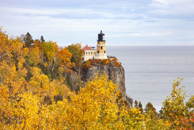 Lighthouse by sea against sky